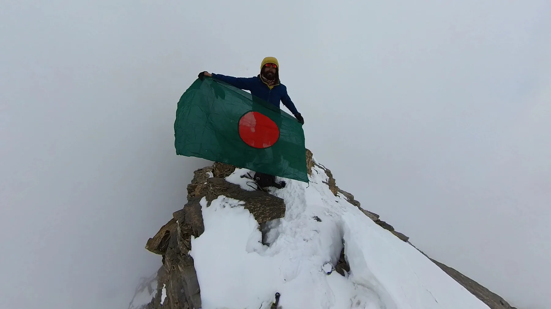 Intiaz Mahmud holds the Bangladesh flag on the snowy summit of Pisang Peak in Nepal