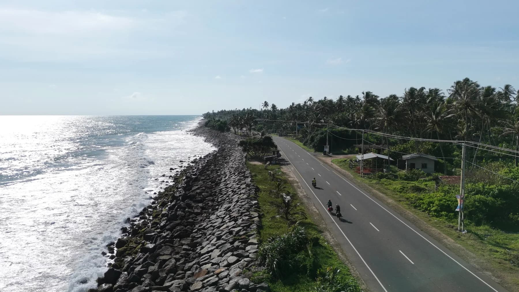 Aerial view of cyclists on Sri Lanka’s marine drive with the ocean on one side and palms on the other