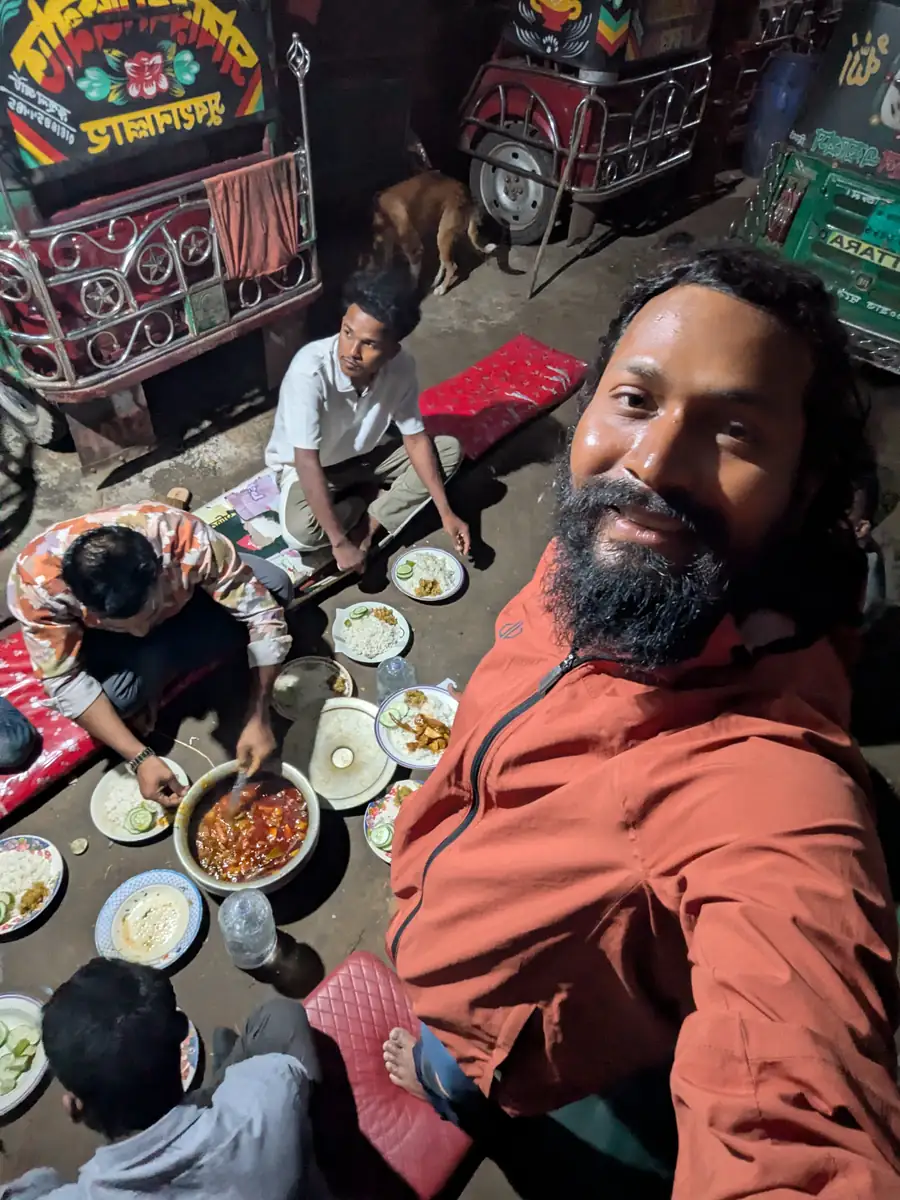 Intiaz Mahmud shares a meal with local people among parked autorickshaws