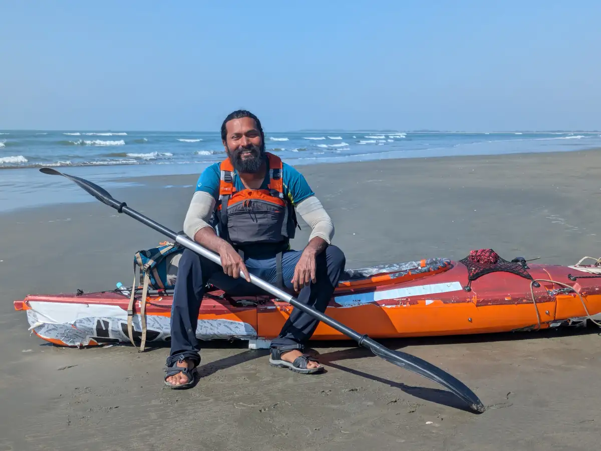 Intiaz Mahmud sits on his kayak holding a paddle on the beach at Cox’s Bazar