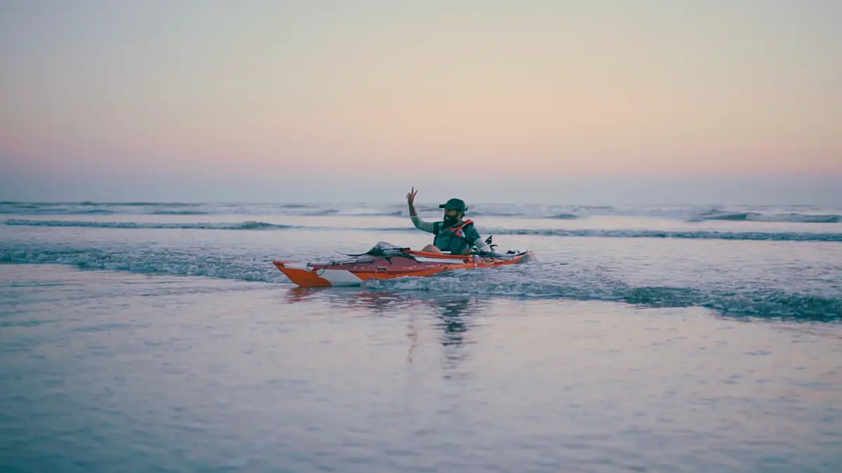 Intiaz Mahmud raises a hand from his kayak in the evening surf at Shah Porir Dwip