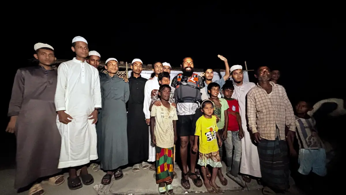 Intiaz Mahmud stands with people gathered after his arrival at Shah Porir Dwip at night