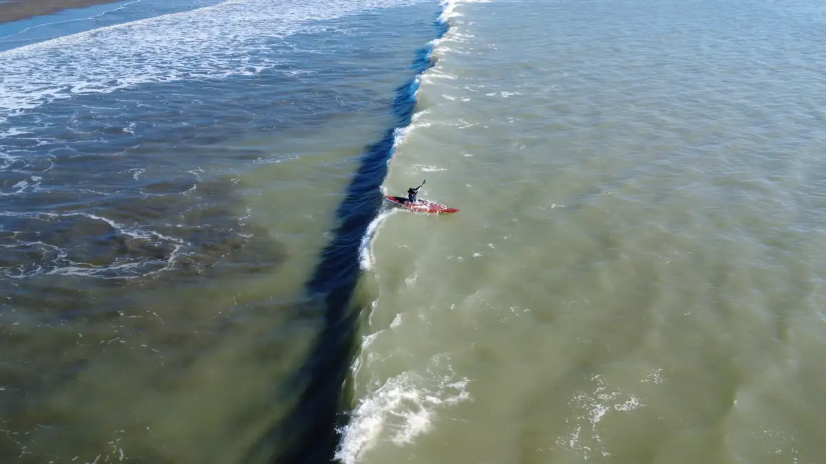 An aerial view of Intiaz Mahmud kayaking beside a breaking wave near Teknaf